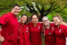 A group of nursing students in red scrubs.